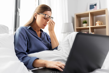 Image showing tired woman in glasses with laptop in bed at home