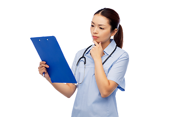 Image showing pensive asian female doctor with clipboard