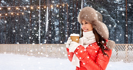 Image showing happy woman with coffee cup over winter ice rink