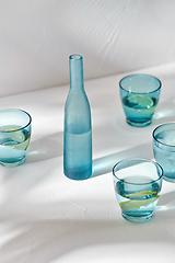 Image showing glasses with water and lemons on white background