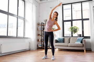 Image showing smiling young woman exercising at home