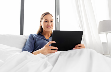 Image showing young woman with tablet pc in bed at home bedroom