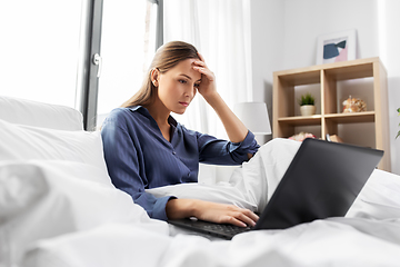 Image showing stressed young woman with laptop in bed at home