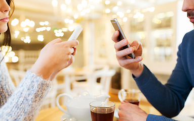 Image showing close up of couple with smartphones at cafe