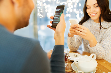 Image showing happy couple with smartphones drinking tea at cafe