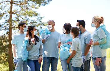 Image showing volunteers in masks with garbage bags talking