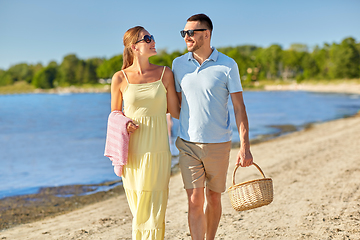 Image showing happy couple with picnic basket walking on beach