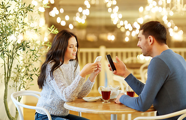 Image showing happy couple with smartphones drinking tea at cafe