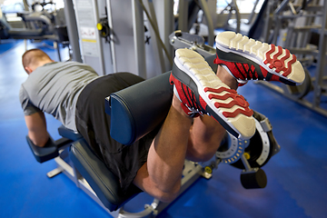 Image showing man flexing leg muscles on gym machine