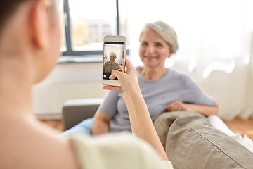 Image showing adult daughter photographing senior mother at home