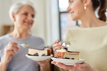 Image showing old mother and adult daughter eating cake at home