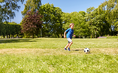 Image showing happy little boy with ball playing soccer at park