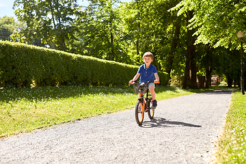 Image showing happy little boy riding bicycle at summer park