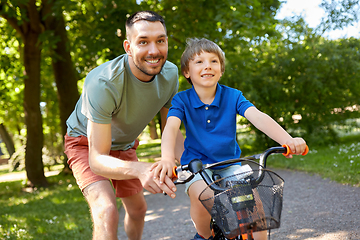 Image showing father teaching little son to ride bicycle at park