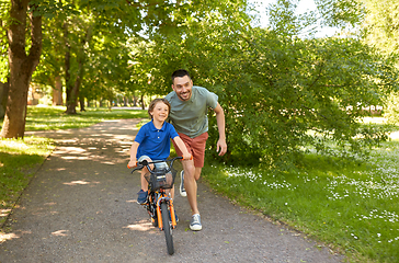 Image showing father teaching little son to ride bicycle at park