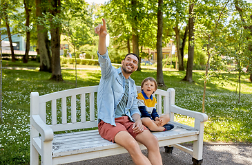 Image showing father showing something to son sitting on bench