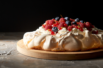 Image showing pavlova meringue cake with berries on wooden board