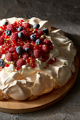 Image showing pavlova meringue cake with berries on wooden board