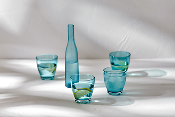 Image showing glasses with water and lemons on white background