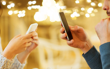 Image showing close up of couple with smartphones at cafe