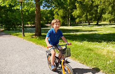 Image showing happy little boy riding bicycle at summer park