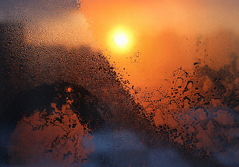 Image showing Ice patterns, water drops and sunlight on a winter window glasss