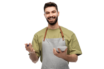 Image showing smiling waiter in apron taking notes to notepad