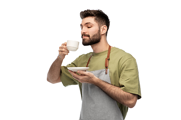 Image showing happy barista or waiter in apron drinking coffee