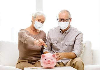 Image showing old couple in masks putting coin into piggy bank