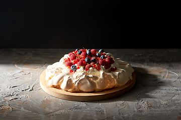 Image showing pavlova meringue cake with berries on wooden board