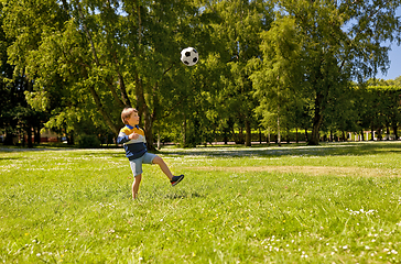 Image showing happy little boy with ball playing soccer at park