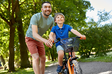 Image showing father teaching little son to ride bicycle at park