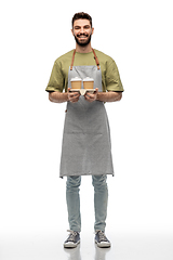 Image showing happy smiling barman in apron with takeaway coffee