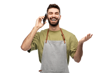 Image showing happy barman in apron calling on smartphone