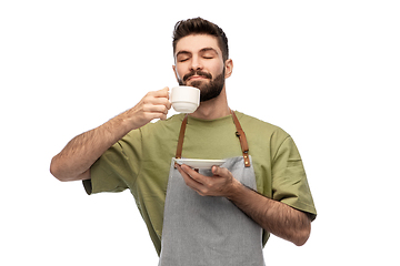 Image showing happy barista or waiter in apron drinking coffee