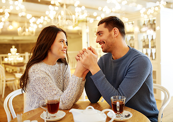 Image showing happy couple with tea holding hands at restaurant