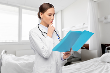 Image showing thinking female doctor with folder at hospital