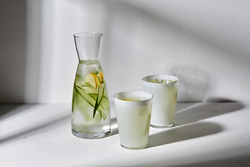 Image showing glasses with lemon water and cucumber on table