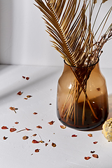 Image showing decorative dried flowers in glass vase and petals