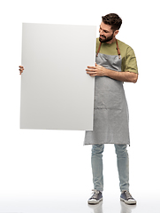 Image showing happy barman in apron holding empty white board