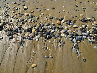 Image showing Wet sea pebbles on the sand