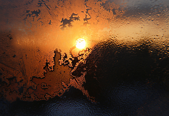 Image showing Ice patterns, water drops and sunlight on a winter window glasss