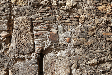 Image showing Texture of an old wall of stones and bricks lit by sunlight