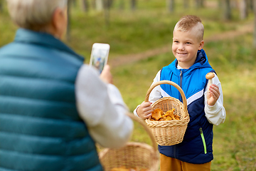 Image showing grandmother photographing grandson with mushrooms