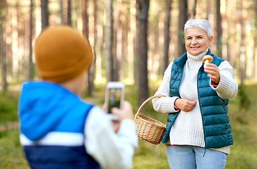 Image showing grandson photographing grandmother with mushroom