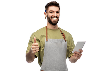 Image showing smiling waiter in apron taking notes to notepad