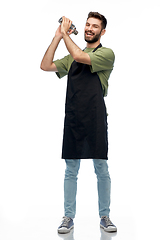 Image showing happy barman in apron with shaker preparing drink