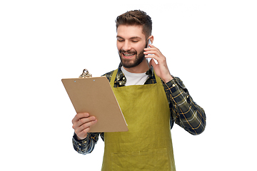 Image showing male gardener with clipboard calling on smartphone