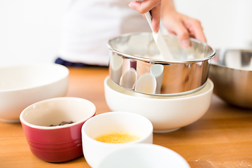 Image showing Woman sifting flour through a sieve in a bowl