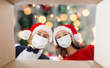 Image showing couple in medical masks opening christmas gift box